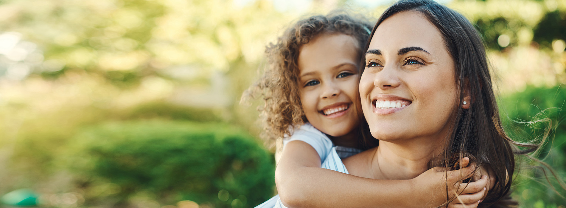 A woman and a child in an outdoor setting, embracing each other.