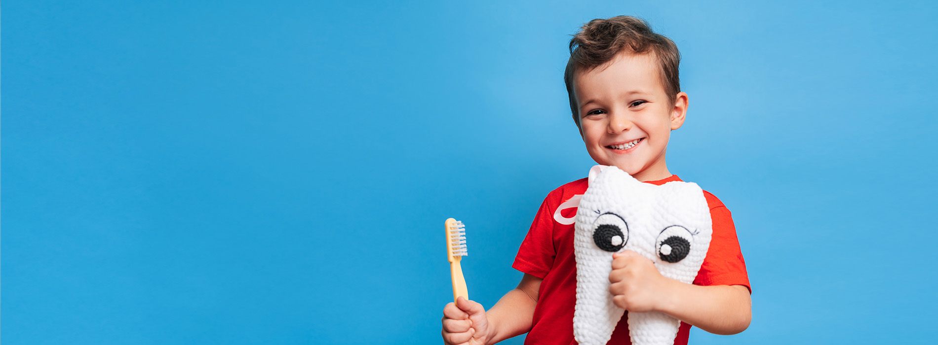 A young boy holding a toy, smiling and posing for the camera.