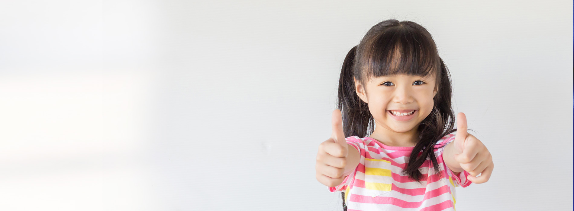 The image features a young child, likely of Asian descent, smiling and giving a thumbs-up gesture in front of a plain background.