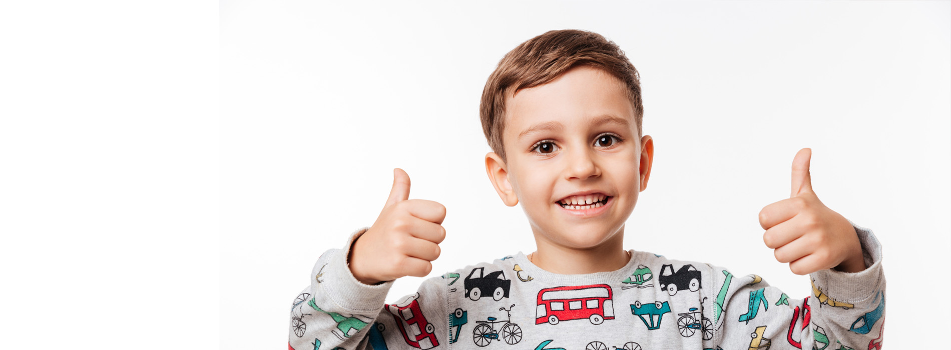 A young boy giving a thumbs up gesture in front of a white background.