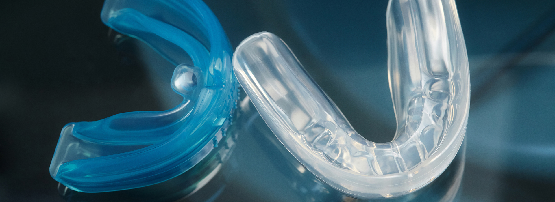 The image shows a close-up of a blue plastic toothbrush head with bristles, set against a blurred background.